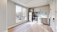 Located at 918 N Broad St in Philadelphia's vibrant North Broad corridor, this one-bedroom, one-bathroom unit offers a thoughtfully designed layout with contemporary finishes throughout. Light wood laminate flooring runs continuously through the living areas, reflecting natural light and lending a clean, modern aesthetic.

The kitchen is a standout feature, anchored by a large picture window that frames views of the surrounding Philadelphia cityscape. It is equipped with stainless steel appliances, including a refrigerator, range, and microwave, complemented by light wood cabinetry, light blue subway tile backsplash, and a single-basin sink — delivering both style and functionality in a compact footprint.

The living area features exposed industrial-style HVAC ductwork along the ceiling, adding an urban loft character to the space. A keypad-secured entry door provides modern security and convenience.

The bedroom is a well-proportioned private retreat with its own window for natural light and direct access to a dedicated closet. Exposed ductwork continues here, maintaining the consistent industrial aesthetic.

The bathroom is efficiently appointed with large-format neutral tile, a soaking tub with overhead shower and matte black fixtures, a vanity with storage, and warm recessed lighting — delivering a clean, spa-like feel.

This unit combines urban industrial design elements with modern comforts, ideally situated near Philadelphia's arts, dining, and transit corridors.