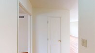 This single-floor residence offers a clean, functional layout spread across several well-defined rooms, all unified by warm-toned hardwood flooring that runs continuously throughout the living spaces. The open, neutral color palette of cream and white walls creates a bright, airy atmosphere that complements the natural light filtering in through multi-pane windows found in several rooms.

The living areas are generously proportioned, providing ample space for flexible furniture arrangements. Multiple rooms are equipped with ceiling fans fitted with light fixtures, contributing to both comfort and illumination. Radiant baseboard heaters are positioned beneath the windows in several rooms, ensuring efficient heating throughout.

The bedrooms feature closet storage, with at least one room offering dual closets, adding practical storage capacity. Windows in the bedrooms frame outdoor views of the surrounding neighborhood.

The kitchen is distinctively styled with a classic black-and-white checkered tile floor, white cabinetry, a gas range, a refrigerator, and a sink with a tiled backsplash — delivering a timeless, utilitarian aesthetic.

The bathroom is finished with white wall tile and includes a window that brings in natural light and exterior views. The overall layout, as revealed in the floor plan, is efficiently organized, connecting all rooms in a cohesive and accessible flow.