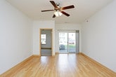 This single-floor unit offers a clean, functional layout with a cohesive design throughout. The open living area is finished with light hardwood flooring that extends throughout the main spaces, complemented by bright white walls and ceiling fans with integrated lighting that contribute to an airy, well-lit atmosphere. A sliding glass door floods the living area with natural light while providing direct outdoor access, and a secondary entry door further enhances connectivity to the exterior.

The kitchen flows seamlessly from the living space and is equipped with light wood cabinetry, dark countertops, and a full suite of black appliances, including a range, microwave, dishwasher, and refrigerator. Pendant lighting above the kitchen area adds a practical finishing touch. Ample cabinet space above and below the counters supports everyday storage needs.

The bedroom is generously sized, featuring plush carpeting, a ceiling fan, and a window that allows in natural light and outdoor views. The bathroom is finished with light tile flooring, a wood-toned vanity with a white countertop, a large mirror, and a full tub and shower combination with chrome fixtures, maintaining the unit's consistent, neutral aesthetic throughout.