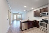 Located at 5403 W 96th Ave in Westminster, Colorado, this thoughtfully designed one-bedroom, one-bathroom residence offers a functional and modern living experience across a single floor. The open-concept layout seamlessly connects the kitchen, dining, and living areas, creating a spacious and airy feel throughout.

The kitchen is a standout feature, showcasing rich dark-stained cabinetry, granite countertops, a classic white subway tile backsplash, and a full suite of stainless steel appliances including a refrigerator, range, microwave, and dishwasher. A peninsula with an integrated sink provides additional prep space and serves as a natural divider between the kitchen and the open living area. Wood-look plank flooring flows throughout the main living spaces, complemented by recessed lighting and a ceiling fan.

The living room benefits from natural light through large windows and a glass door that opens to the outdoors. The bedroom is carpeted for comfort and also features a ceiling fan. The full bathroom includes a soaking tub with shower, granite-topped vanity, and matching dark cabinetry. Additional highlights include a dedicated office space, a pantry, and a convenient in-unit laundry room with side-by-side washer and dryer. Crown molding and neutral tones throughout lend a clean, polished finish to the entire space.