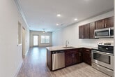 Located at 5403 W 96th Ave in Westminster, Colorado, this thoughtfully designed one-bedroom, one-bathroom residence offers a functional and modern living experience across a single floor. The open-concept layout seamlessly connects the kitchen, dining, and living areas, creating a spacious and airy feel throughout.

The kitchen is a standout feature, showcasing rich dark-stained cabinetry, granite countertops, a classic white subway tile backsplash, and a full suite of stainless steel appliances including a refrigerator, range, microwave, and dishwasher. A peninsula with an integrated sink provides additional prep space and serves as a natural divider between the kitchen and the open living area. Wood-look plank flooring flows throughout the main living spaces, complemented by recessed lighting and a ceiling fan.

The living room benefits from natural light through large windows and a glass door that opens to the outdoors. The bedroom is carpeted for comfort and also features a ceiling fan. The full bathroom includes a soaking tub with shower, granite-topped vanity, and matching dark cabinetry. Additional highlights include a dedicated office space, a pantry, and a convenient in-unit laundry room with side-by-side washer and dryer. Crown molding and neutral tones throughout lend a clean, polished finish to the entire space.