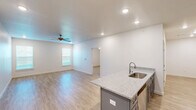 Located at 130 N Cedar St in Centerton, Arkansas, this well-appointed one-bedroom, one-bathroom unit offers a thoughtfully designed single-floor layout with clean, modern finishes throughout. Light wood-style flooring extends across the entire space, complementing the crisp white walls and creating a bright, cohesive aesthetic.

The open-concept kitchen and living area serves as the heart of the unit. The kitchen is outfitted with gray shaker-style cabinetry, granite-look countertops, and a full suite of stainless steel appliances including a range, microwave, and refrigerator with ice maker. A central kitchen island with a built-in sink and matching countertop provides additional prep space and serves as a natural divider between the kitchen and living area. Recessed lighting and a ceiling fan keep the space well-lit and comfortable.

The generously sized bedroom features its own ceiling fan, a natural light-filled window with blinds, and direct access to multiple closets, including a large walk-in closet with dual hanging rods on multiple walls. The combined bathroom and laundry room offers a full tub-shower unit with clean white surround panels and brushed nickel fixtures. The layout efficiently maximizes every square foot, making this a functional and attractive living space.
