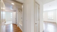 Located at 3900 PGA Pkwy in Frisco, TX, this well-appointed 2-bedroom, 2-bathroom residence offers a thoughtfully designed single-level layout. The open-concept kitchen and living area serves as the heart of the home, showcasing a large center island with a built-in sink, crisp white cabinetry, a neutral tile backsplash, and a full suite of stainless steel appliances including a refrigerator, range, microwave, and dishwasher. Recessed lighting and wood-look flooring throughout the main living areas contribute to a bright, contemporary atmosphere. Large windows with blinds invite abundant natural light and offer views of the surrounding Frisco landscape. The spacious primary bedroom features plush carpeting, a ceiling fan, and access to a well-appointed ensuite bathroom complete with a double-sink vanity, white quartz countertops, a walk-in glass shower with subway tile, and direct entry to a dedicated walk-in closet with built-in shelving and hanging rods. The second bedroom is also carpeted, includes a ceiling fan and window, and is served by a second full bathroom featuring a soaking tub, single vanity, and wood-look flooring. Two hallways provide functional flow throughout the home, completing this clean, modern residence.