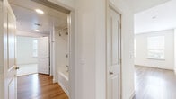 Located at 3900 PGA Pkwy in Frisco, TX, this well-appointed 2-bedroom, 2-bathroom residence offers a thoughtfully designed single-level layout. The open-concept kitchen and living area serves as the heart of the home, showcasing a large center island with a built-in sink, crisp white cabinetry, a neutral tile backsplash, and a full suite of stainless steel appliances including a refrigerator, range, microwave, and dishwasher. Recessed lighting and wood-look flooring throughout the main living areas contribute to a bright, contemporary atmosphere. Large windows with blinds invite abundant natural light and offer views of the surrounding Frisco landscape. The spacious primary bedroom features plush carpeting, a ceiling fan, and access to a well-appointed ensuite bathroom complete with a double-sink vanity, white quartz countertops, a walk-in glass shower with subway tile, and direct entry to a dedicated walk-in closet with built-in shelving and hanging rods. The second bedroom is also carpeted, includes a ceiling fan and window, and is served by a second full bathroom featuring a soaking tub, single vanity, and wood-look flooring. Two hallways provide functional flow throughout the home, completing this clean, modern residence.