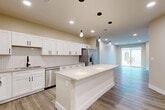 Located at 130 N 39th St in Omaha, Nebraska, this thoughtfully designed 2-bedroom, 3-bathroom unit offers a clean, contemporary aesthetic across a well-proportioned single-floor layout. The open-concept kitchen and living area serves as the heart of the home, anchored by a large central island with quartz-style countertops and stylish pendant lighting. The kitchen is fully equipped with stainless steel appliances, including a range, microwave, dishwasher, and French door refrigerator, complemented by white shaker cabinetry with matte black hardware and a subway tile backsplash. Wood-look plank flooring runs throughout the main living areas, adding warmth and continuity. The spacious living room is bathed in natural light from large sliding glass doors that open to a private outdoor deck area. Both bedrooms feature plush carpeting and ceiling fans, with the primary bedroom offering access to a dedicated walk-in closet fitted with wire shelving systems. The three bathrooms are finished with neutral tones, wood-look flooring, and matte black fixtures, including a tub-shower combination. The unit's warm beige palette, recessed lighting, and modern finishes create a cohesive and inviting atmosphere throughout.