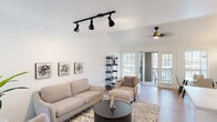 This single-story unit at 16755 Ella Blvd in Houston, TX presents a cohesive modern aesthetic throughout, characterized by a crisp white and neutral color palette, light wood-look flooring, and black hardware accents that create a consistent design language across every room.

The living area is generously proportioned, featuring vaulted ceilings, black track lighting, a ceiling fan, and glass doors that open directly onto a balcony, allowing natural light to flow freely into the space. The layout comfortably accommodates multiple seating arrangements, making it well-suited for both everyday living and entertaining.

Adjacent to the living area, the dining space benefits from large shuttered windows that invite additional natural light, while crown molding adds a refined architectural detail.

The kitchen is outfitted with white shaker-style cabinetry, quartz countertops, a subway tile backsplash, stainless steel appliances, and matte black hardware, delivering a clean, functional workspace.

The bedrooms are calm and well-lit, each featuring light flooring, ceiling fans, and windows with exterior views. One bedroom offers a notable water view, enhancing its serene ambiance.

Both bathrooms maintain the space's clean aesthetic, featuring quartz vanities, white tilework, tub-shower combinations, and black fixtures throughout.