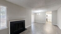 Located at Kimberly Village Lane in Marietta, GA, this 2-bedroom, 2-bathroom residence offers a thoughtfully designed single-floor layout with modern updates throughout. The living room serves as the heart of the home, anchored by a classic fireplace with a white-trimmed mantle and complemented by dark wood-look flooring that adds warmth and visual depth. A textured ceiling and neutral gray walls create a clean, contemporary backdrop throughout the space. The dining area features light wood-look flooring, a stylish multi-pendant chandelier, and a sliding glass door that invites natural light. The kitchen is well-appointed with crisp white shaker-style cabinetry, marble-pattern countertops, a subway tile backsplash, and stainless steel appliances, offering both style and functionality. Both bedrooms are comfortably sized, with the primary bedroom providing generous space, large windows with natural light, and wood-look flooring. The two bathrooms are neatly finished — one featuring a marble-top vanity with brushed nickel hardware and a framed mirror, and the other with a full tub-shower combination. A dedicated closet adds practical storage to round out this well-organized residence.