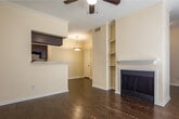 Located at 808 Gladstell St in Conroe, TX, this single-floor residence offers a well-designed layout with a cohesive blend of comfort and practicality. The living room is a standout space, showcasing rich dark hardwood-style flooring, crown molding, a ceiling fan, and a classic fireplace flanked by built-in shelving — an ideal focal point for the room. Natural light filters in through blinds-covered windows, creating a bright and welcoming atmosphere. An open pass-through connects the living area to the kitchen, which features dark espresso cabinetry, marble-style countertops, black appliances including a refrigerator and range, and continued dark wood-style flooring that ties the space together. A separate dining or flex area with matching flooring, crown molding, a ceiling fan, and direct access to the outdoors via a glass door adds versatility to the layout. The bedrooms are finished with plush carpeting, ceiling fans, and natural light from windows. The bathrooms are well-appointed, with one featuring a dark vanity with marble-style countertops, a large mirror, and wood-style flooring, while another includes a full tub-shower combo with classic white tile surround. This unit combines functional design with tasteful finishes throughout.