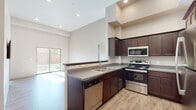 This single-floor residence at Remington Way in Bozeman, Montana offers a well-designed layout with a clean, contemporary aesthetic throughout. The kitchen serves as a central feature of the home, outfitted with rich dark-wood cabinetry extending to impressive heights, stainless steel appliances including a refrigerator, electric range, microwave, and dishwasher, and a double-basin sink set into a gray countertop peninsula. Soaring ceilings in the kitchen and living areas amplify the sense of openness, while recessed lighting provides consistent illumination throughout.

Light wood-style plank flooring runs throughout the main living and sleeping areas, contributing to a warm, cohesive feel. The bedrooms are bright and well-proportioned, each benefiting from natural light through large windows that frame views of the surrounding neighborhood. The taller-than-standard ceilings in the sleeping areas further enhance the spacious character of the rooms.

The bathrooms feature gray-toned vanity cabinetry with ample storage, a single-basin sink, lighted mirror, and a glass-enclosed shower. An in-unit laundry area is also present. Throughout the home, neutral wall tones, modern door hardware, and consistent finishes create a polished, move-in-ready environment.