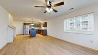 This two-floor space is designed with functionality and comfort in mind, offering a well-organized layout across its levels. The main living area features an open-concept design where the kitchen flows seamlessly into the living space. Light hardwood-style flooring runs throughout, complemented by neutral white walls and clean baseboard trim. A ceiling fan with integrated lighting anchors the living area, while recessed lighting illuminates the kitchen. The kitchen is appointed with rich, dark-stained wood cabinetry, granite-style countertops, stainless steel appliances including a refrigerator and range, a center island for additional workspace, and a pendant light fixture above. A window above the sink allows natural light into the space.

Bedrooms are carpeted for comfort and equipped with ceiling fans. Multiple windows fitted with blinds bring in natural light throughout. One bedroom features a generous walk-in closet with wire shelving systems providing ample storage. A bathroom includes light hardwood-style flooring and clean, simple fixtures. A dedicated in-unit laundry closet houses a full-sized washer and dryer, adding everyday convenience to the overall well-appointed layout.