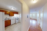 Located at 605 Middle St in Weymouth, MA, this two-bedroom, one-bathroom residence offers a practical and comfortable single-floor layout. Warm hardwood flooring runs throughout the main living areas and bedrooms, lending a cohesive and inviting feel to the space. The kitchen is equipped with rich wood cabinetry, granite-style countertops, and white appliances including an electric range. A charming pass-through window connects the kitchen to the living area, enhancing the open feel between the two spaces. The living room is bright and airy, benefiting from natural light streaming through large windows, and includes a private exterior door. Both bedrooms are well-proportioned, with the primary bedroom offering two windows that invite generous natural light and views of the surroundings. Three closets are distributed throughout the unit, providing ample storage. The full bathroom features a tub-shower combination, a vanity with under-sink storage, and tile flooring. Baseboard heating is present throughout the unit, and a wall-mounted A/C unit in the living area ensures year-round comfort. The entrance and hallway provide a welcoming transition into the home, completing a functional and thoughtfully arranged floor plan.