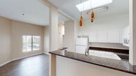 Located at 600 Front Street in San Diego, this single-floor residence offers a thoughtfully designed layout with a clean, neutral aesthetic throughout. The open-concept kitchen serves as a central feature, showcasing rich dark granite countertops with a breakfast bar peninsula, crisp white cabinetry, and a skylight that floods the space with natural light. Stylish pendant lighting adds a contemporary accent above the kitchen area.

The living areas are finished with warm hardwood-style flooring that extends consistently throughout the unit, creating a cohesive and inviting atmosphere. Large windows fitted with vertical blinds allow generous amounts of natural light into the living and bedroom spaces, while also providing views of the surrounding San Diego streetscape. A wall-mounted HVAC unit ensures year-round climate comfort in the living area.

The bedrooms are well-proportioned, each featuring hardwood-style floors, neutral warm-toned walls, and ample natural light. One bedroom includes a mirrored sliding-door closet with built-in shelving, offering practical storage solutions.

The bathrooms are finished in a clean, functional style. The full bathroom features a wide vanity with a large mirror, bright overhead lighting, and a glass-door shower enclosure. A second bathroom provides additional convenience with an overhead storage cabinet. The overall ambiance is bright, clean, and move-in ready.