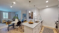 This thoughtfully designed single-floor residence offers a seamless blend of modern aesthetics and functional living. The open-concept kitchen serves as the heart of the home, anchored by a granite-topped island with an undermount sink, pendant lighting, white cabinetry, stainless steel appliances, and a subway tile backsplash. Light wood-tone flooring flows throughout, connecting the kitchen to the adjacent dining area and a bright, inviting living room. The living space features large windows dressed with plantation shutters, flooding the room with natural light, and includes a wall-mounted television and a sectional seating area ideal for relaxing.

The residence includes two bedrooms, each with ceiling fans, natural light from shuttered windows, and distinct design character. One bedroom features an art deco-inspired iron headboard, while the other showcases a upholstered blue headboard with warm, coordinated accents.

Both bathrooms are finished with granite countertops, light wood flooring, and clean white cabinetry. Each includes a glass-enclosed shower, providing a sleek and spa-like atmosphere. One bathroom offers a Jack-and-Jill layout connecting directly to a bedroom, adding convenience and privacy. Throughout the space, a neutral, light-filled palette and curated décor create a cohesive and welcoming ambiance.