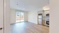 Located in the heart of Los Angeles' Koreatown neighborhood, this modern 1-bedroom, 1-bathroom unit offers a clean, contemporary design with an efficient and well-appointed layout. Light hardwood flooring flows throughout the space, complementing the crisp white walls and creating a bright, airy ambiance.

The open-concept living and kitchen area serves as the heart of the unit. The kitchen is outfitted with sleek two-tone cabinetry — white upper cabinets paired with warm wood-toned lower cabinets — along with stainless steel appliances including a range, microwave, and dishwasher, plus a herringbone tile backsplash and a matte black faucet. A large sliding glass door floods the living area with natural light and frames views of the surrounding Los Angeles cityscape.

The bedroom is a calm, well-lit retreat featuring light hardwood flooring, a tall vertical window with city views, closet access, and a clean, minimalist aesthetic. Two closets provide ample storage throughout the unit.

The bathroom features a classic black-and-white hexagon tile floor, a tub-shower combination with marble-style tile surround, a wood-accented vanity with an integrated sink, and a modern mirror. In-unit laundry accommodations add convenience to this efficiently designed urban residence.