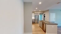 North Grove B2A is a well-appointed 2-bedroom, 2-bathroom apartment spanning 920 square feet on a single floor in Riverside, CA 92501. The modern exterior features a contemporary multi-story building with clean lines and a neutral facade. Inside, the open-concept kitchen and living area is anchored by a stylish kitchen outfitted with two-tone gray and white shaker cabinetry, stainless steel appliances including a gas range, over-the-range microwave, and refrigerator, complemented by a white subway tile backsplash and light wood-style flooring. The living area offers abundant natural light through large windows and a sliding glass door that provides outdoor views and access. Both bedrooms feature plush carpeting; the primary bedroom measures 130 square feet and includes a walk-in closet with built-in wire shelving. The two bathrooms are finished with light wood-look flooring, gray cabinetry with dark countertops, and full shower/tub combinations with tile surrounds. A dedicated laundry room and two hallways add to the unit's functionality, making this apartment a practical and contemporary living space.