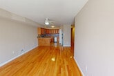 Located at 521 Liberty Ave in Staten Island, NY, this two-story home offers four bedrooms and two bathrooms across two floors. The main floor is generously proportioned and centers around an open-concept living and kitchen area, unified by gleaming hardwood floors that run throughout. The kitchen is well-appointed with warm honey-toned cabinetry, granite countertops, a decorative tile backsplash, and a full suite of stainless steel appliances including a gas range, built-in microwave, and dishwasher. A peninsula counter provides additional workspace and casual dining. The living area is bright and airy, with natural light streaming through large windows and a front entry door that opens to the outdoors. Ceiling fans are present in multiple rooms. The bedrooms feature the same hardwood flooring and ceiling fans, with the primary bedroom offering a notably spacious feel and a large window that fills the room with natural light. The upper floor accommodates additional bedrooms, accessible via staircase. The two bathrooms are distinctly styled: one features white tile surrounds with a tub-shower combo and a dark-framed vanity, while the second showcases floor-to-ceiling marble-style tile and a sleek sliding glass shower enclosure.