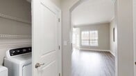 This modern 2-bedroom apartment at Lenox Farms offers 1000 square feet of thoughtfully designed living space. The open floor plan creates a seamless flow between rooms, enhanced by light wood-toned flooring throughout. Large windows in every room flood the space with natural light, complementing the neutral color palette.

The heart of the home is a sleek, galley-style kitchen featuring white cabinetry, stainless steel appliances, and ample counter space. The living area is generously sized, with architectural details like arched openings adding character. The primary bedroom, measuring 210 square feet, provides a spacious retreat.

The bathroom boasts a contemporary design with a double vanity, large mirror, and modern lighting. Additional amenities include a ceiling fan in the living area for comfort and blinds on all windows for privacy. The apartment's layout efficiently utilizes space, creating an atmosphere that feels both open and intimate. Perfect for those seeking a blend of style and functionality in a modern living environment.