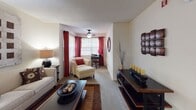 This single-floor residence is designed with an open, flowing layout that connects the kitchen, dining, and living areas into one cohesive shared space. The kitchen is well-appointed with warm honey-toned cabinetry, granite-style countertops, a built-in microwave, an electric range, and a dishwasher. A peninsula with bar seating extends into the dining area, creating a natural gathering point and making the kitchen both functional and social. Track lighting overhead ensures the space is well-illuminated throughout.

The dining area transitions seamlessly into the carpeted living room, which features a ceiling fan, a large window dressed with bold red curtains, and ample room for comfortable seating arrangements. The living room benefits from natural light filtering in through the window, adding warmth to the relaxed ambiance.

The bedroom is a standout feature of the space, distinguished by a striking deep-orange accent wall that lends the room a bold, energetic character. Carpeted flooring, a window with curtains, and access to an adjacent closet contribute to its cozy and functional design.

The bathroom is equipped with a full tub and shower combination with tiled surround, a toilet, and vanity with storage, all finished with tile flooring for a clean, practical aesthetic. Throughout the residence, the design maintains a warm and welcoming tone with consistent use of rich earth tones and thoughtful details.