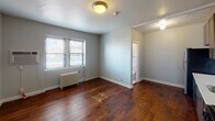 Located at 1201 Hawthorne Ave in Minneapolis's Lowry Hill neighborhood, this unit offers a thoughtfully designed single-floor layout with rich, dark hardwood flooring that runs throughout the main living and bedroom areas, adding warmth and character to the space.

The main living area is bright and open, featuring a large window with street views, a classic cast-iron radiator for heating, and a wall-mounted AC unit. The connected bathroom is accessible directly from this room, offering a clean and efficient layout.

The kitchen is well-equipped with dark wood cabinetry reaching to the ceiling, providing ample storage. A white subway tile backsplash adds a timeless aesthetic, complemented by stainless steel appliances including a gas range, over-the-range microwave, dishwasher, and refrigerator. Light countertops contrast the cabinetry, and a single-basin sink completes the functional workspace.

The bathroom showcases full floor-to-ceiling white subway tile surrounding a tub-shower combination, with a window that brings in natural light while maintaining privacy. The clean, classic tiling gives the bathroom a crisp, timeless feel.

Overall, the space blends classic architectural details with modern conveniences, making it a practical and attractive residence in the heart of Minneapolis.