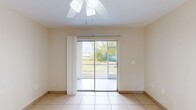 Located at 3027 Broadway in Fort Myers, FL, this one-bedroom, one-bathroom unit offers a compact and efficiently designed single-floor layout. Light-toned ceramic tile flooring runs consistently throughout the entire space, lending a clean and cohesive look to every room.

The living and dining areas share an open feel, brightened by a sliding glass door that opens to an outdoor view of the surrounding greenery. A ceiling fan with an integrated light fixture keeps the space comfortable in Florida's warm climate. Neutral, warm-beige walls contribute to the bright, airy ambiance throughout.

The kitchen is equipped with white cabinetry, granite-style countertops, a stainless steel sink, a dishwasher, and a range, with a window above the sink allowing for additional natural light. The layout maximizes the available counter and storage space efficiently.

The bedroom features its own ceiling fan, a window with exterior views, and a sliding glass door providing access to an outdoor area. The bathroom includes a vanity with granite-style countertops, white cabinetry, a wall mirror, and a full tub-shower combination, all finished with tile flooring. A connecting hallway ties the rooms together, completing this straightforward and functional floor plan.