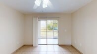 Located at 3027 Broadway in Fort Myers, FL, this one-bedroom, one-bathroom unit offers a compact and efficiently designed single-floor layout. Light-toned ceramic tile flooring runs consistently throughout the entire space, lending a clean and cohesive look to every room.

The living and dining areas share an open feel, brightened by a sliding glass door that opens to an outdoor view of the surrounding greenery. A ceiling fan with an integrated light fixture keeps the space comfortable in Florida's warm climate. Neutral, warm-beige walls contribute to the bright, airy ambiance throughout.

The kitchen is equipped with white cabinetry, granite-style countertops, a stainless steel sink, a dishwasher, and a range, with a window above the sink allowing for additional natural light. The layout maximizes the available counter and storage space efficiently.

The bedroom features its own ceiling fan, a window with exterior views, and a sliding glass door providing access to an outdoor area. The bathroom includes a vanity with granite-style countertops, white cabinetry, a wall mirror, and a full tub-shower combination, all finished with tile flooring. A connecting hallway ties the rooms together, completing this straightforward and functional floor plan.