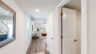 Located in Spring Hill, Kansas, this two-story home offers a well-designed layout spread across two floors. The main level features a bright, open-concept living room and kitchen area connected by wood-look plank flooring throughout. The living room is equipped with a ceiling fan, large sliding glass door that invites natural light, and a sleek staircase with metal balusters leading to the upper level. The kitchen is outfitted with dark taupe shaker-style cabinetry, granite countertops, a subway tile backsplash, and a full suite of stainless steel appliances, including a refrigerator, range, microwave, and dishwasher. A dedicated hallway connects the main entry with the living area, offering a clean transition between spaces. Upstairs, the generously sized primary bedroom features vaulted ceilings, plush carpeting, a natural light-filled window, and a double-door closet. The second bedroom also features vaulted ceilings and carpeted flooring. A flexible office space with carpet and a bright window provides an ideal work-from-home setup. Both bathrooms are well-appointed, with one featuring a tub-shower combination and granite-topped vanity. The home's neutral palette and thoughtful layout create a cohesive and functional living environment throughout.