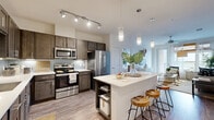 Located on Babcock Road in San Antonio, TX, this well-appointed 2-bedroom, 2-bathroom residence offers a thoughtfully designed single-level layout. The kitchen is a standout feature, showcasing rich dark cabinetry, light quartz countertops, a subway tile backsplash, stainless steel appliances, and a central island with pendant lighting — ideal for both cooking and casual dining. Wood-look flooring flows throughout the main living areas, lending warmth and continuity to the space. The living room is bright and inviting, with large windows that draw in natural light and provide a relaxing retreat. Each bedroom is carpeted and comfortably sized, with the primary bedroom offering a ceiling fan and access to a private en-suite bathroom featuring a walk-in glass shower, granite-topped vanity, and wood-look tile flooring. The second bathroom includes a shower-tub combination and matching granite vanity. Both bedrooms are served by dedicated closets, with the primary closet offering wrap-around shelving and hanging rods for ample storage. A private balcony extends the living space outdoors, offering pleasant views of the surrounding tree canopy and neighborhood. The overall ambiance is clean, modern, and comfortable throughout.