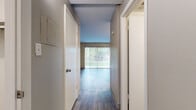 Located at 1117 City Park Ave in Fort Collins, Colorado, this efficiently designed studio unit offers a smart, single-floor layout that maximizes every square foot. The open living area is anchored by durable wood-look flooring that runs throughout the space, lending a warm, cohesive feel. Painted concrete block walls add a distinct architectural texture, while a large sliding glass door floods the room with natural light and provides a direct view of the greenery outside. Vertical blinds offer flexible light control and privacy.

The kitchen is defined by a peninsula with a dark granite-style countertop that separates it from the living area, creating a natural division of space. White upper cabinetry, a built-in range, sink, and refrigerator complete the functional cooking area, all beneath a flush-mount ceiling light.

A hallway leads to two closets, offering generous storage for a unit of this scale. The bathroom features a combined tub and shower with clean white tile surround, a vanity with a dark speckled countertop and undermount sink, and wood-look flooring that ties the space together. The overall ambiance is clean, modern, and practical, making this unit a well-appointed option in the heart of Fort Collins.