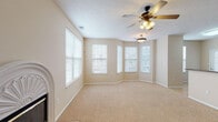 This single-story home offers a thoughtfully designed layout with a warm, neutral color palette throughout. The living room serves as a central gathering space, highlighted by an elegantly arched fireplace surround and flanked by windows fitted with horizontal blinds that invite abundant natural light. A ceiling fan adds both function and visual interest overhead.

A separate sitting or flex room features a distinctive bay window configuration, creating an open, airy feel with views to the exterior. An additional carpeted room with sliding glass doors and vertical blinds provides convenient outdoor access, while another ceiling fan maintains a comfortable atmosphere.

The kitchen is well-equipped with rich honey-toned wood cabinetry offering extensive storage, light-toned countertops, tile flooring, and a full suite of black appliances including a refrigerator with ice maker, electric range, built-in microwave, and dishwasher.

Bedrooms are carpeted and feature neutral walls, natural light from windows, and walk-in closet access. The bathrooms are finished with tile flooring, white cabinetry with dark countertops, and tub-shower combinations, providing a clean and functional design. Throughout the home, consistent finishes and ceiling fans in each room create a cohesive, comfortable living environment.