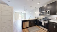 Located at 2100 W Littleton Blvd in Littleton, CO, this thoughtfully designed 2-bedroom, 2-bathroom residence offers a well-appointed single-level layout with modern finishes throughout. The open-concept kitchen and living area serves as the heart of the home, featuring dark espresso cabinetry, stainless steel appliances including a gas range, microwave, and refrigerator, along with a striking two-tone kitchen island with a blue base and white quartz countertop, complemented by a tile backsplash and pendant lighting. Light wood-style flooring flows through the main living areas, which are bathed in natural light from large windows and a sliding glass door that opens to the outdoors. A ceiling fan adds comfort to the airy living room. The spacious primary bedroom features plush carpeting, a ceiling fan, and direct access to a well-organized walk-in closet with built-in shelving and dual hanging rods. The primary bathroom offers a dual-sink vanity with dark cabinetry, quartz countertops, and large-format tile flooring. The second bedroom is bright and carpeted, while the second bathroom includes a tub/shower combo with decorative tile accents and matching dark vanity cabinetry. Neutral tones throughout create a clean, cohesive aesthetic.