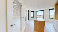Located at 1280 Union St NE in Washington, DC, this modern one-bedroom, one-bathroom residence offers a thoughtfully designed layout across a single floor. Light hardwood flooring flows throughout the open-concept living area and bedroom, creating a warm, cohesive aesthetic.

The kitchen is a standout feature, outfitted with light wood cabinetry, white upper cabinets, a clean quartz countertop, stainless steel gas range, built-in oven, and microwave. A central island with a white countertop provides additional workspace and casual seating, making the kitchen both functional and visually striking.

The living area transitions seamlessly from the kitchen, benefiting from an abundance of natural light streaming through large, black-framed floor-to-ceiling windows that frame expansive views of the Washington, DC cityscape. The bedroom continues this design language, featuring oversized sliding glass doors that open to a private balcony, along with corner windows that flood the room with light and offer panoramic urban views.

The bathroom is finished with large-format neutral tile flooring, a sleek wall-mounted vanity, and a glass-enclosed walk-in shower with full-height tile surround. A dedicated closet and hallway complete the well-organized floor plan, offering practical storage within this efficiently designed urban residence.