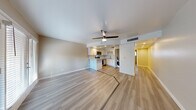 This single-floor residence offers a thoughtfully designed open-concept layout with a cohesive, modern aesthetic. Light wood-style luxury vinyl flooring runs throughout the space, unifying each room with a clean, contemporary feel. Neutral-toned walls and white trim complement the bright, airy atmosphere found across all areas.

The living area is generously proportioned, featuring a ceiling fan with integrated lighting and a set of French doors that invite natural light and provide outdoor access. The kitchen is positioned in open view of the living space and is outfitted with white shaker-style cabinetry, light stone countertops, a classic white subway tile backsplash with contrasting grout, and a full suite of stainless steel appliances including a range, microwave, and dishwasher. A dedicated laundry area with a washing machine is conveniently accessible nearby.

The bedroom offers a comfortable layout with a ceiling fan, a window with outdoor views, and a mirrored sliding closet. The bathroom is finished in a clean, all-white palette featuring a tub-shower combination, a white vanity, and light wood-style tile flooring. Recessed lighting and ceiling fans throughout enhance both functionality and ambiance.