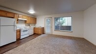 This single-floor residential unit offers a practical and well-organized layout designed for comfortable everyday living. The open living and dining area is finished with plush wall-to-wall carpeting and neutral-toned walls, creating a warm and inviting atmosphere. A large window floods the space with natural light and provides views of the surrounding neighborhood, while a door leads directly to the outdoors, adding convenience and connectivity to the exterior.

The kitchen is efficiently laid out and features warm honey-toned wood cabinetry offering generous storage, light countertops, a white electric range with overhead ventilation, a dishwasher, and a sink positioned beneath additional cabinetry. The kitchen floor transitions to durable wood-look vinyl, providing easy maintenance in a high-use area.

The bedroom is a quiet, carpeted retreat with smooth white walls and a window that brings in natural light and neighborhood views. The private entry area features wood-look vinyl flooring and includes a wall-mounted thermostat, a clean six-panel door, and a smoke detector overhead, reflecting thoughtful safety and comfort considerations.

The bathroom is neatly appointed with wood-look vinyl flooring, a full soaking tub and shower combo with a curved curtain rod, a toilet, and a vanity with warm wood cabinetry and a single sink. The overall design of the unit is clean, functional, and move-in ready.