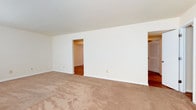 Located at 21 Sacramento Drive, this two-floor space offers a straightforward and functional layout designed to accommodate a variety of needs. The interior is finished with a clean, neutral color scheme, featuring crisp white walls that create a bright and open atmosphere throughout.

The main living area is generously proportioned, finished with wall-to-wall carpeting in a warm beige tone that adds comfort underfoot. The room opens to adjoining spaces through open doorways, offering a sense of flow and connectivity between areas. Through these openings, rich hardwood flooring is visible, providing a appealing contrast to the carpeted main space and adding a touch of warmth to the overall aesthetic.

The layout reveals thoughtful spatial organization, with doorways leading to additional rooms that appear to include closeted storage, suggesting well-considered functionality. The consistent white trim and baseboards throughout tie the spaces together cohesively.

Spanning two floors, the property provides ample room across its levels, making it a versatile space suited for residential use. The clean, move-in-ready condition of the interiors, combined with the combination of carpet and hardwood surfaces, gives the home a practical yet comfortable character at 21 Sacramento Drive.