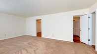 Located at 21 Sacramento Drive, this two-floor space offers a straightforward and functional layout designed to accommodate a variety of needs. The interior is finished with a clean, neutral color scheme, featuring crisp white walls that create a bright and open atmosphere throughout.

The main living area is generously proportioned, finished with wall-to-wall carpeting in a warm beige tone that adds comfort underfoot. The room opens to adjoining spaces through open doorways, offering a sense of flow and connectivity between areas. Through these openings, rich hardwood flooring is visible, providing a appealing contrast to the carpeted main space and adding a touch of warmth to the overall aesthetic.

The layout reveals thoughtful spatial organization, with doorways leading to additional rooms that appear to include closeted storage, suggesting well-considered functionality. The consistent white trim and baseboards throughout tie the spaces together cohesively.

Spanning two floors, the property provides ample room across its levels, making it a versatile space suited for residential use. The clean, move-in-ready condition of the interiors, combined with the combination of carpet and hardwood surfaces, gives the home a practical yet comfortable character at 21 Sacramento Drive.