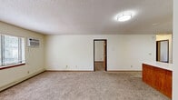 Located at 1707 16th St SE in Saint Cloud, Minnesota, this single-floor home offers a practical and functional layout across four bedrooms and one bathroom. The kitchen is well-equipped with wood-accented cabinetry, white appliances including a refrigerator, electric range, and dishwasher, plus generous counter space and durable wood-look flooring. A breakfast bar connects the kitchen to the adjoining living area, which features carpet flooring, textured ceilings, and multiple windows that invite natural light. The spacious primary bedroom is notably generous in size, complete with a ceiling fan, built-in closet with shelving, and carpeted floors. The three additional bedrooms are similarly finished with carpet, textured ceilings, and windows providing natural light and ventilation. Each bedroom benefits from baseboard heating, ensuring comfort during Minnesota winters. The bathroom features a tub/shower combination and tile flooring. Throughout the home, warm wood-tone baseboards and trim provide a cohesive design element. The open-concept connection between the kitchen and living space enhances the overall sense of roominess, making this a well-suited home for larger households.