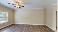 This two-story home in Fayetteville, NC offers a practical and comfortable layout spread across two well-proportioned floors. The main level features a welcoming living area with rich hardwood-style flooring, crown molding, and a ceiling fan, creating a bright and inviting atmosphere with natural light filtering through the windows. The kitchen is a standout feature, boasting granite countertops, warm wood cabinetry, tile backsplash, a peninsula with a stainless steel sink, black appliances, and elegant pendant lighting — ideal for both everyday cooking and entertaining. A convenient half or full bathroom is also located on the main floor. Upstairs, the spacious primary bedroom features plush carpeting, a ceiling fan, and a private en-suite bathroom, offering a comfortable retreat. The second bedroom is equally well-sized with carpeted floors, a ceiling fan, a closet, and a window with garden views. The bathrooms throughout are finished with wood vanities, white countertops, tile flooring, and tub-shower combinations with clean white surrounds. Two closets provide ample storage, and a staircase connects both levels seamlessly. The home's consistent warm neutral palette and quality finishes lend a cohesive, move-in-ready appeal throughout.