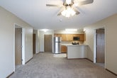 This single-floor unit is thoughtfully laid out to maximize functionality across its living spaces. The kitchen is designed in a galley configuration, featuring warm oak cabinetry, light-toned laminate countertops, and stainless steel appliances including a refrigerator, electric range, built-in microwave, and dishwasher. Tile flooring runs throughout the kitchen, providing a durable and easy-to-clean surface.

The open living area is finished with wall-to-wall neutral carpet and features a ceiling fan with integrated lighting. A peninsula counter connects the kitchen to the living space in one configuration, offering a natural division while maintaining an open feel. Warm beige walls and textured ceilings are consistent throughout the unit.

The bedrooms are carpeted and generously sized, each featuring natural light from windows fitted with horizontal blinds. Closet space is provided via bifold-door closets with built-in hanging rods. One bedroom includes a direct view into the kitchen area.

Two full bathrooms serve the unit, each featuring a tub-shower combination with chrome fixtures, a toilet, tile flooring, and vanity cabinetry. Wood-toned doors and warm baseboards carry through the unit, contributing to a cohesive, practical aesthetic.