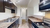 This single-floor residence offers a functional and comfortable layout designed for everyday living. The galley-style kitchen is a standout feature, showcasing dark espresso cabinetry, granite-look countertops, a double stainless steel sink, a gas range, a dishwasher, and a built-in microwave. Track lighting overhead illuminates the space efficiently, while tile flooring adds durability. Adjacent to the kitchen is a dedicated pantry closet outfitted with multiple wire shelving tiers, providing ample storage for dry goods and kitchen essentials. An in-unit laundry room offers added convenience with washer and dryer hookups and tile flooring.

The bedrooms are carpeted and bathed in natural light through sizable windows fitted with horizontal blinds, offering pleasant views of lush greenery. One bedroom includes a closet with a hanging rod, while another features a dual-window configuration that enhances the sense of space and airflow.

Two bathrooms serve the residence, each featuring dark wood vanities, white countertops, large mirrors, and chrome fixtures. The bathrooms are finished with tile flooring and include towel bars and adequate lighting. Throughout the home, warm neutral wall tones create a cohesive and inviting atmosphere, making this a practical and move-in-ready space.
