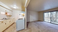 This single-floor residence at 4224 Hickory Rd in Mishawaka, Indiana, offers a straightforward and functional layout designed for comfortable everyday living. The kitchen is positioned near the entry and features white appliances, including a gas range and refrigerator, alongside light wood cabinetry that provides ample storage. A structural column and partial wall define the kitchen area while maintaining an open sightline to the adjoining living space.

The living area is generously proportioned, finished with wall-to-wall carpet in a neutral tone that continues throughout the home. A sliding glass door with vertical blinds opens to an outdoor balcony, allowing natural light to fill the room and offering views of surrounding trees, lending the space a calm, natural ambiance.

The bedroom is a well-sized, carpeted room with a window fitted with horizontal blinds, bringing in additional natural light and exterior views. The room provides a quiet and comfortable retreat.

The bathroom is cleanly finished with tile flooring in an earthy tone, a full tub-and-shower combination with white tile surround, a toilet, and a vanity with a single basin sink and wood-trimmed cabinetry. The overall palette throughout the home is light and neutral, contributing to a bright and welcoming atmosphere.