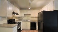 Located at 1053 Rifle Range Rd in the desirable Mt. Pleasant, South Carolina community, this single-floor residence offers a straightforward and functional living environment. The kitchen serves as a central highlight of the space, showcasing crisp white raised-panel cabinetry that provides generous storage both above and below the countertops. A suite of black appliances — including a refrigerator, electric range, dishwasher, and under-cabinet range hood — gives the kitchen a cohesive, classic look. The laminate countertops offer ample workspace, and the stainless double-basin sink is positioned along the back wall for a practical workflow. Track lighting mounted on the ceiling provides targeted, adjustable illumination throughout the kitchen. The wood-style flooring adds warmth to the space and complements the neutral wall tones. A textured ceiling further defines the interior character of the home. The overall layout is designed with efficiency in mind, making the most of the available space while maintaining a clean, orderly aesthetic throughout. This residence presents a well-maintained and move-in ready option in the Mt. Pleasant area.