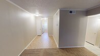 Located at 9371 Mansfield Rd in Shreveport, Louisiana, this single-story unit offers a practical and well-organized layout designed for comfortable everyday living. The living area is generously sized, featuring warm carpet flooring, crown molding, a textured ceiling, and a large window that allows natural light to fill the room. A front entry door is conveniently situated adjacent to the window, providing easy access directly into the living space.

The galley-style kitchen is efficiently arranged with white cabinetry lining both walls, offering ample storage. It is equipped with a coil electric range, a refrigerator, a double stainless steel sink, and light-toned countertops. A window above the sink brings in additional natural light.

A hallway connects the living area to the rest of the unit, with light vinyl flooring transitioning from the kitchen zone. The bedroom is carpeted and well-proportioned, featuring a window with blinds and access to a dedicated walk-in closet complete with built-in shelving — a notable storage feature. The bathroom includes a full tub-shower combination with white subway tile surround accented by a decorative mosaic border tile, adding a touch of character. HVAC vents are present throughout, ensuring year-round climate control.