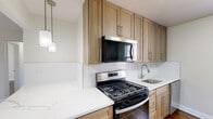 Located at 5 Market St in Clifton, NJ, this well-appointed 2-bedroom, 1-bathroom unit offers a thoughtfully designed single-floor layout that maximizes functionality and comfort. Rich hardwood floors flow throughout the space, complementing the neutral wall tones and white trim that give each room a clean, classic feel.

The open kitchen and living area serves as the heart of the home, showcasing warm wood shaker-style cabinetry, quartz countertops with a subtle marble-like finish, white subway tile backsplash, and a full suite of stainless steel appliances including a gas range, built-in microwave, dishwasher, and refrigerator. A pendant light adds a stylish finishing touch above the counter.

Both bedrooms are generously proportioned, each featuring ceiling fans with light fixtures, large windows that invite ample natural light and views of the surrounding greenery, and classic cast-iron radiators. Three closets are distributed throughout the unit, offering practical storage solutions.

The bathroom is neatly finished with a single-vanity, medicine cabinet mirror, and a tub-shower combination enclosed by sliding glass doors, with a window providing natural ventilation. Additional conveniences include an in-unit laundry area and a central hallway connecting all rooms seamlessly.