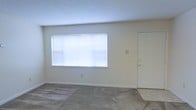 Located at 552 Springridge Rd in Clinton, Mississippi, this single-floor space offers a clean and functional layout designed for comfortable everyday living. The main living area is finished with wall-to-wall carpeting in a neutral tone, providing a soft and welcoming underfoot feel throughout. Smooth, light-colored walls give the interior a bright and airy atmosphere, complementing the natural light that pours in through a large picture window fitted with horizontal blinds for adjustable privacy and light control. A white interior door is positioned conveniently along the same wall, contributing to the room's simple, uncluttered design. The textured ceiling adds a subtle architectural detail that ties the space together. The overall ambiance is calm and understated, making it a versatile space well-suited for a variety of uses. The single-story layout ensures ease of movement throughout, and the neutral finishes provide a solid foundation for personalization. The property's location in Clinton, MS, places it within a well-established community, adding to its overall appeal.