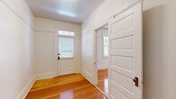This well-proportioned single-story home offers a thoughtfully arranged layout encompassing three bedrooms, two bathrooms, two living areas, a kitchen, and multiple hallways and closets. Warm-toned hardwood floors run throughout the main living spaces and bedrooms, reflecting natural light and contributing to the home's inviting character.

The entry foyer greets visitors with a paneled front door featuring a transom window above, flanked by classic white millwork and wainscoting details that carry throughout the home. The two living areas are connected by an open passage, creating a generous, flowing space ideal for both entertaining and everyday use, with windows on multiple sides drawing in ample daylight.

The primary bedroom is comfortably sized, featuring dual windows with outdoor views and access to a closet. Additional bedrooms are similarly bright, each with hardwood floors and multi-pane windows. Bedroom doors feature traditional five-panel designs consistent with the home's architectural style.

The kitchen is equipped with wood cabinetry, stainless steel appliances including a gas range and dishwasher, and light tile flooring. Both bathrooms carry a classic aesthetic, with black-and-white tile work, wood vanities, and natural light from windows. One bathroom includes a tub, while the other features a glass-enclosed shower stall.