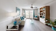 Located at 2100 S Conway Rd in Orlando, Florida, this single-floor, 2-bedroom, 3-bathroom home offers a well-organized layout with a comfortable and cohesive design throughout. The living room features wood-look flooring, a ceiling fan, and large sliding glass doors that allow abundant natural light and outdoor views, creating an open and airy atmosphere. Adjacent to the living area, the dining room includes wood-look flooring, a round glass-top table area, wainscoting details, and a pass-through to the kitchen, which is finished in white cabinetry. The spacious primary bedroom is appointed with plush carpet, a ceiling fan, and a window with outdoor views, complemented by an en-suite bathroom featuring a white vanity with a granite-style countertop and mirrored medicine cabinet. The second bedroom also features carpet flooring, a ceiling fan, and a wide window that brings in natural light. The three bathrooms are clean and functional, with one featuring a full soaking tub and separate toilet area with light wood-look flooring. A hallway connects the bedrooms and shared spaces efficiently. The overall design palette of neutral grays, whites, and wood tones creates a bright, welcoming ambiance throughout the home.