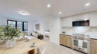 Located at 2971 Shell Road in Brooklyn's 11224 zip code, this thoughtfully designed residence offers five bedrooms, two bathrooms, and two balconies across a single floor. The open-concept kitchen and living area serves as the heart of the home, featuring light wood flooring, recessed lighting, and a seamless flow between cooking, dining, and lounging spaces. The kitchen is appointed with sleek two-tone cabinetry—white upper cabinets paired with natural wood lower units—complemented by a striking gold-veined marble backsplash, stainless steel appliances, and ample counter space. Both bathrooms are finished with floor-to-ceiling marble-style tile, floating vanities, LED-backlit mirrors, and soaking tubs with integrated shower fixtures, exuding a clean, spa-like aesthetic. The five bedrooms are bright and well-proportioned, with large windows dressed in sheer curtains that invite natural light and provide access to or views of the balconies. The primary bedroom offers a comfortable, serene retreat. A welcoming hallway with light hardwood flooring connects the rooms throughout. The overall design palette—neutral whites, warm woods, and stone accents—creates a cohesive, modern ambiance throughout the residence.