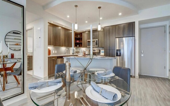 Dining Area With Round Glass Table and Open View Into Stainless Steel Kitchen - Pearl Flagler Village