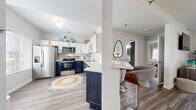 This well-appointed single-floor residence offers two bedrooms, one bathroom, and a thoughtfully designed layout that maximizes its comfortable footprint. The standout feature is the kitchen, which boasts a striking two-tone design with bold navy lower cabinets and crisp white upper cabinets, all accented by brushed gold hardware. Stainless steel appliances — including a refrigerator, range, microwave, and dishwasher — complement the clean white countertops and a gold-finished faucet. A peninsula with bar seating connects the kitchen to the open living area, creating an ideal space for entertaining. Light wood-look flooring runs throughout the main living areas, adding warmth and continuity. The living room is bright and welcoming, with a sliding glass door that invites natural light and provides outdoor views. The primary bedroom is a well-sized retreat with plush carpet flooring, soft neutral walls, and a window that fills the room with natural light. The second bedroom offers similar comfort and style. The bathroom features a clean, full-sized soaking tub and shower combination. Throughout the space, light-toned walls and consistent finishes create a cohesive, modern aesthetic.