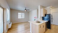 This thoughtfully designed single-floor unit offers a functional and modern living experience across a compact yet efficiently utilized footprint. Light-toned hardwood flooring runs throughout the space, creating visual continuity and a warm, inviting ambiance.

The galley-style kitchen is outfitted with light wood cabinetry featuring black hardware, a full suite of black appliances including a refrigerator, electric range, and dishwasher, complemented by clean white countertops. A peninsula with a sink opens toward the living area, enhancing the open-concept feel. The combined living and dining area is bright and airy, with natural light streaming through multiple windows fitted with blinds. The dining nook is accented by a mid-century modern multi-bulb chandelier, adding a decorative focal point.

The living area features a ceiling fan with integrated lighting and a wall-mounted HVAC unit, providing year-round climate control. A glass door offers views of the surrounding neighborhood.

The bedroom is a comfortable, well-proportioned retreat with a ceiling fan, a window with neighborhood views, and a dedicated closet with a hanging rod. The bathroom is finished with distinctive patterned tile flooring, a combination tub and shower, and a window providing natural ventilation. The unit also includes a separate walk-in closet for additional storage.